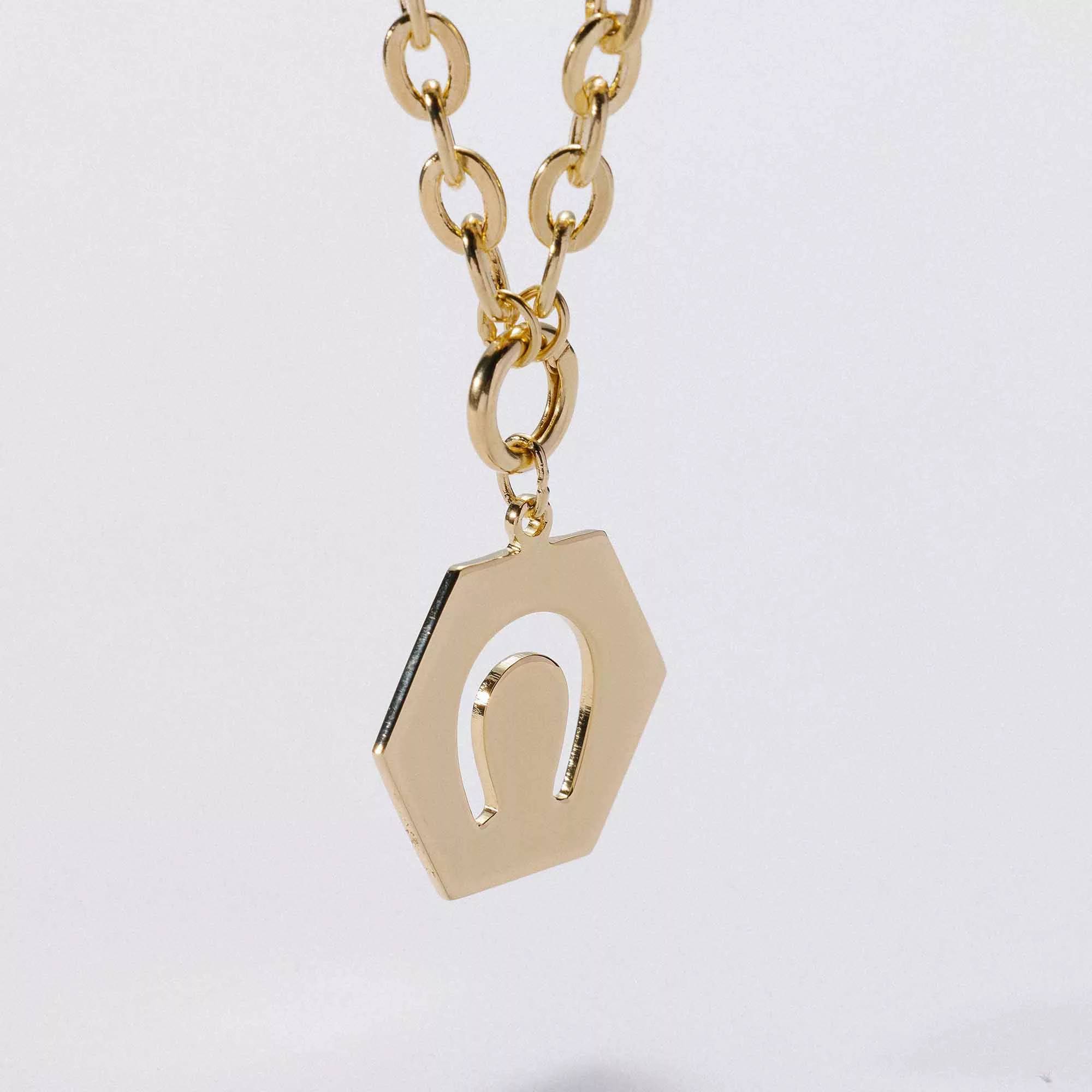 &LIVY Luck in Motion Expandable Necklace gold close-up detail of hexagonal Luck in Motion charm with horseshoe cutout design on classic rolo intention chain
