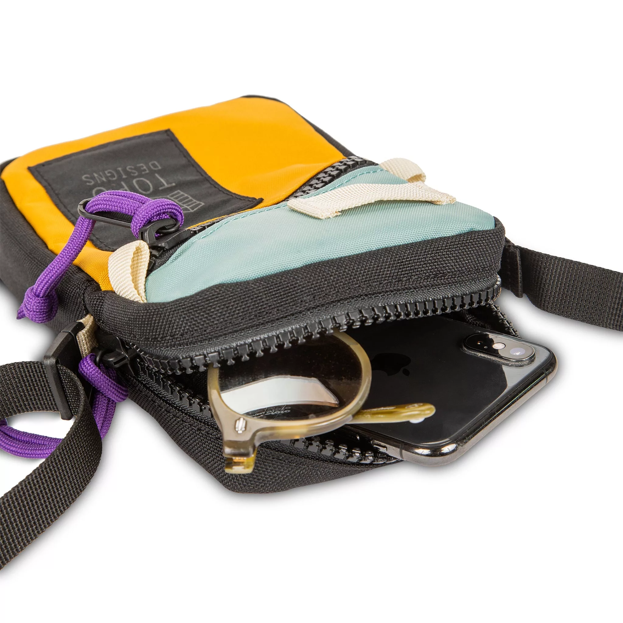 Topo Designs Mini Shoulder Bag crossbody travel purse in Sage Mustard detail showing zipper opening with sunglasses and iPhone inside.