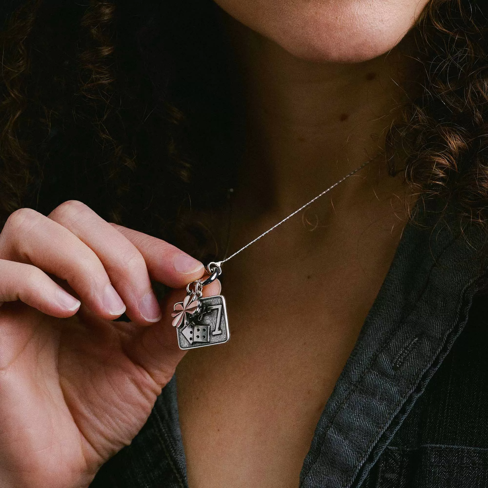 &LIVY Take a Chance Expandable Necklace in silver worn by model showing Lucky 7 dice charm and four-leaf clover charm held in hand