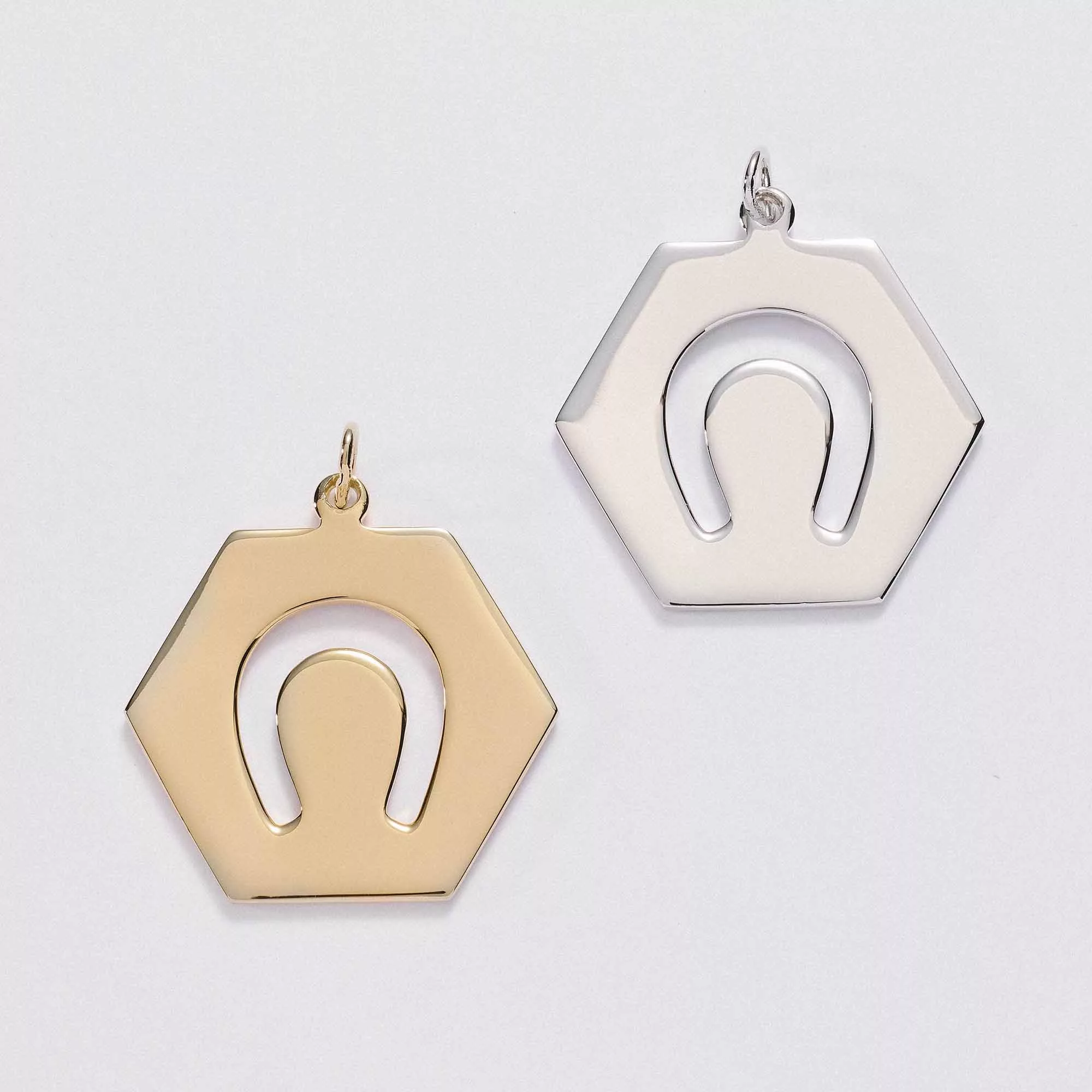 &LIVY Luck in Motion Charm both gold and silver hexagonal pendants with horseshoe cutout design side by side