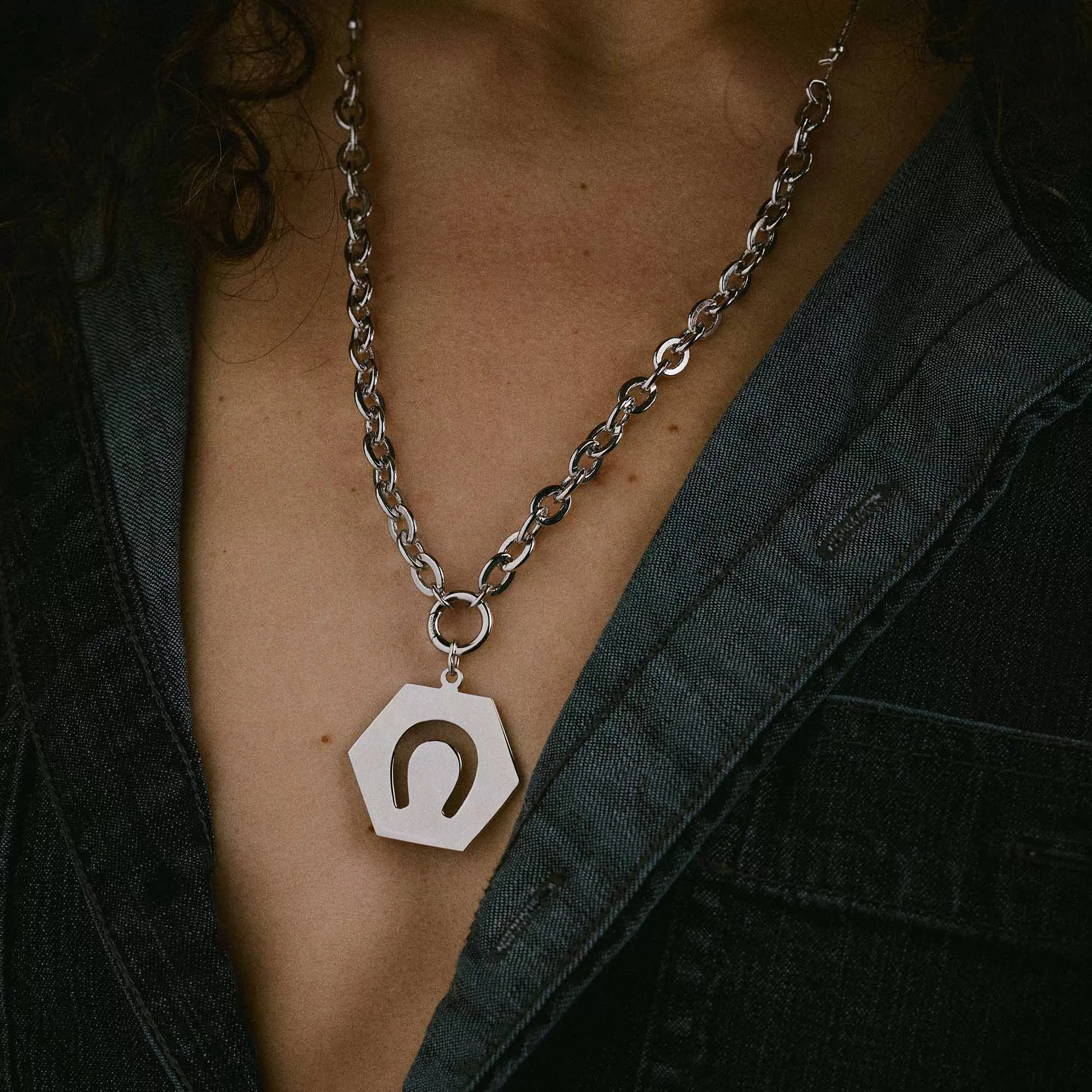 &LIVY Luck in Motion Expandable Necklace in silver worn by model featuring hexagonal Luck in Motion charm with horseshoe design on classic rolo intention chain