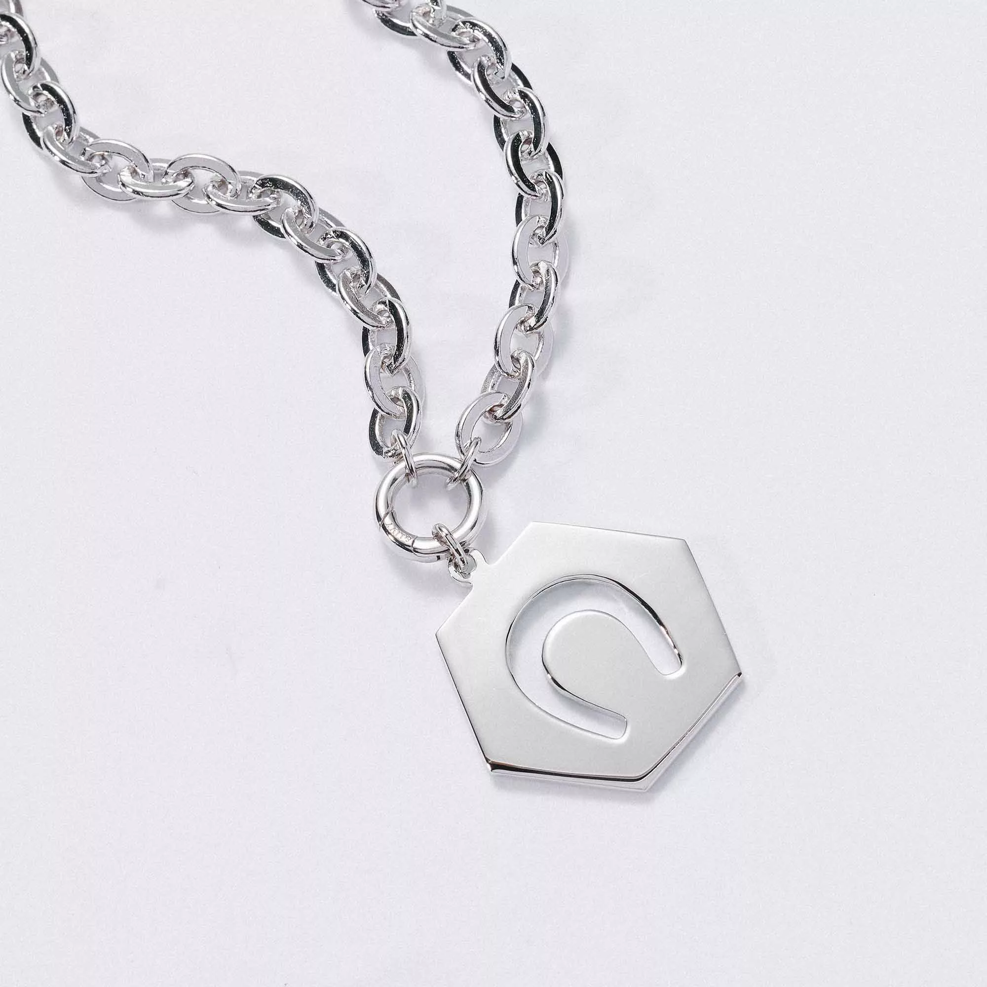 &LIVY Luck in Motion Expandable Necklace in silver close-up of hexagonal Luck in Motion charm with horseshoe cutout design on classic rolo intention chain