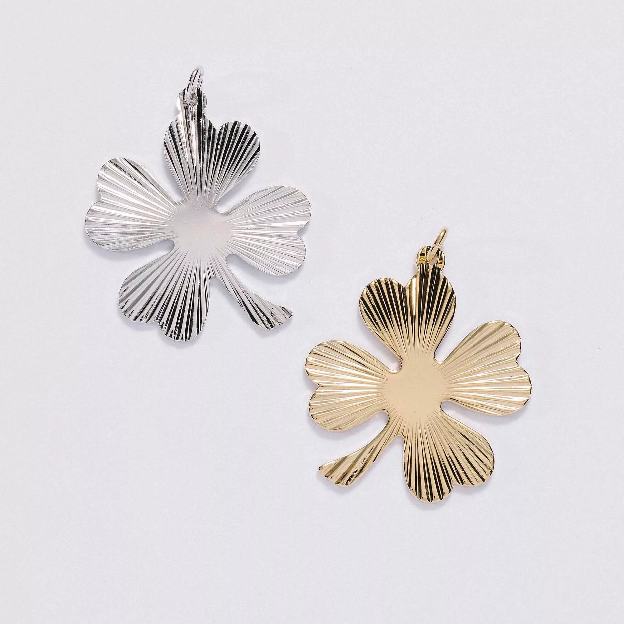 &LIVY Shine On Clover Charm in both silver and gold four-leaf clover pendants with radial sunburst texture