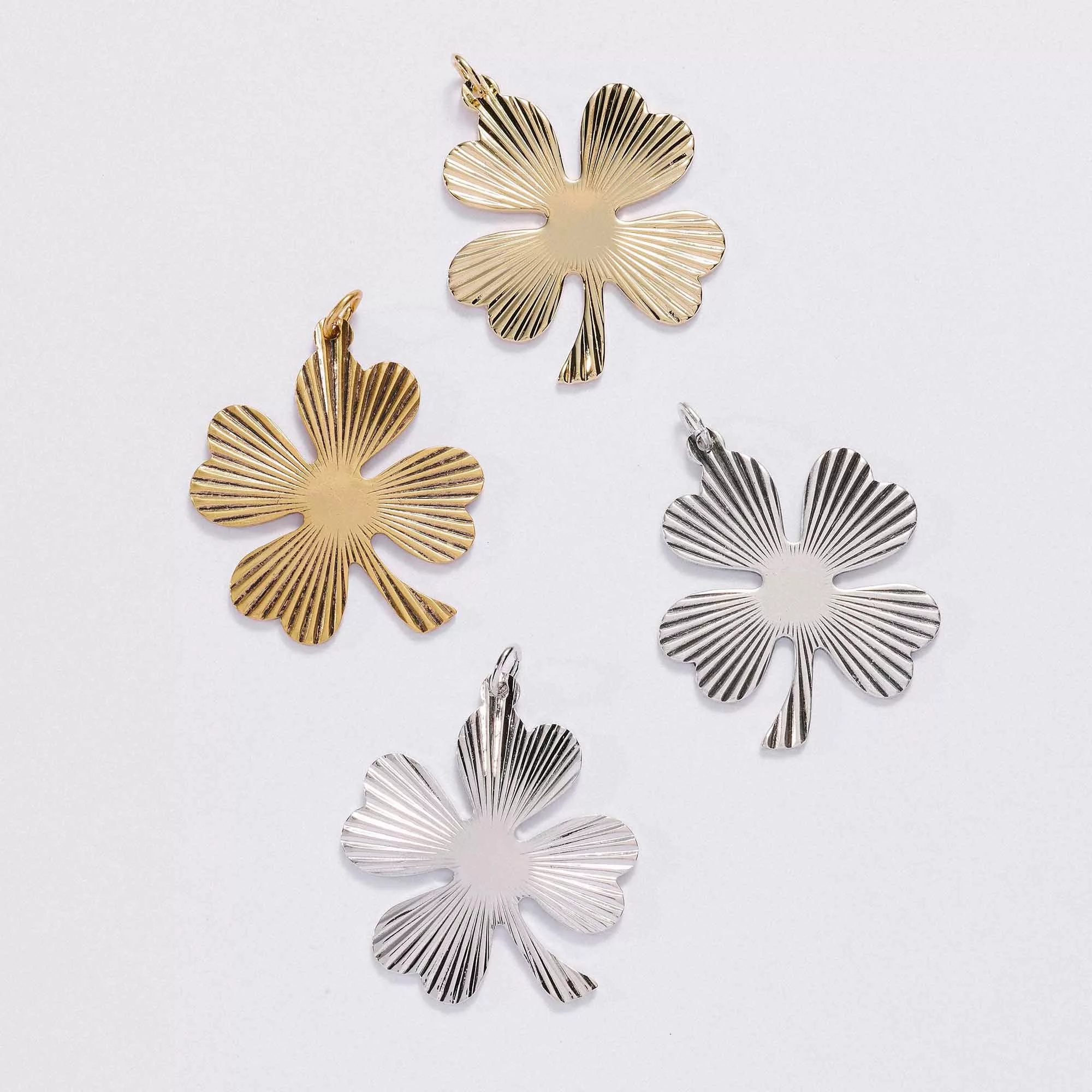 &LIVY Shine On Clover Charm all four variants finely finished gold finely finished silver antique gold and antique silver four-leaf clover pendants with radial sunburst texture