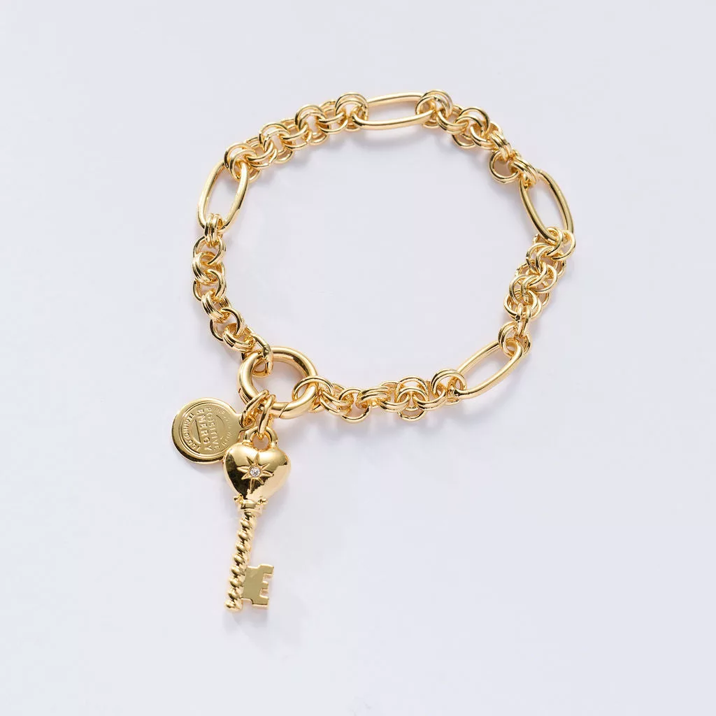 &LIVY Key To My Heart Charm Bracelet in finely finished gold featuring charm link chain with heart-shaped lock charm with gemstone accent branded LIVY coin charm and key charm