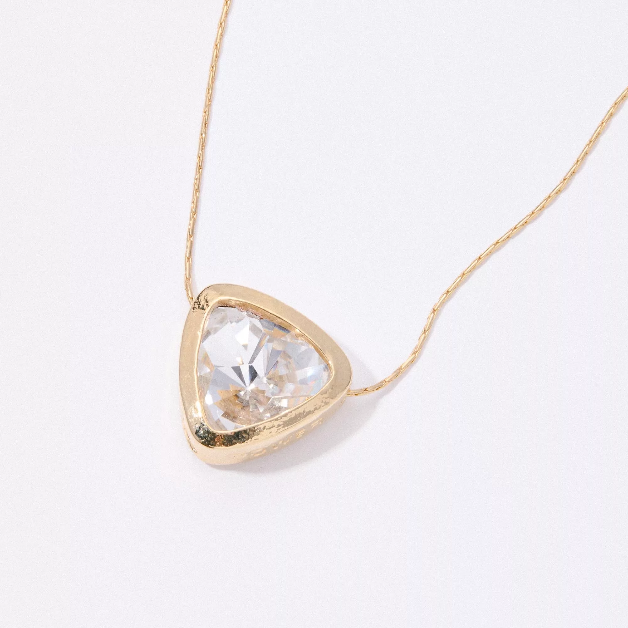 &LIVY Let The Light In Pendant Necklace in finely finished gold close-up detail of clear crystal heart pendant with triangular gold bezel setting on delicate gold chain