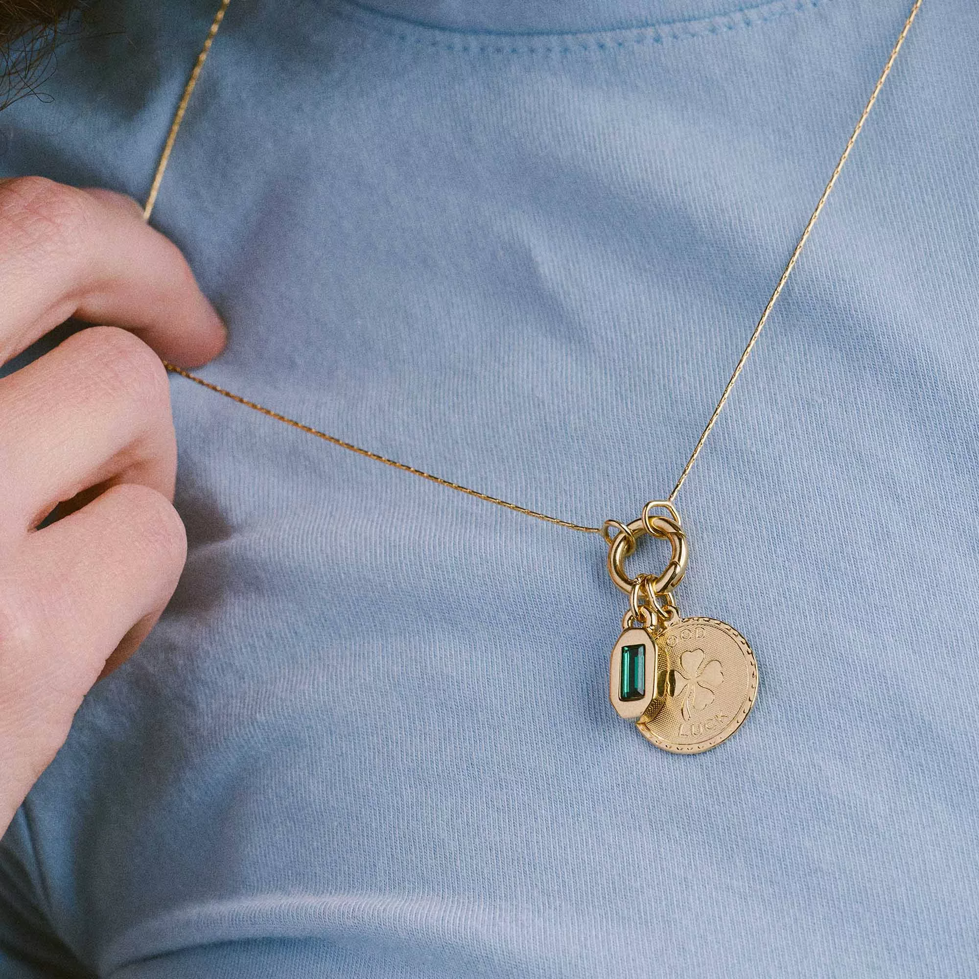 &LIVY Renewed Love Expandable Necklace in gold worn on model close-up showing Good Luck Token coin charm with emerald baguette crystal pendant