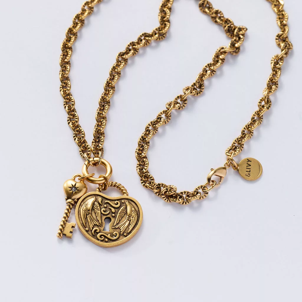 &LIVY The Key to Us Chain Necklace Set in antique gold featuring ornate heart-shaped lock pendant with angel wing design key charm with gemstone accent and branded LIVY coin on layered chain