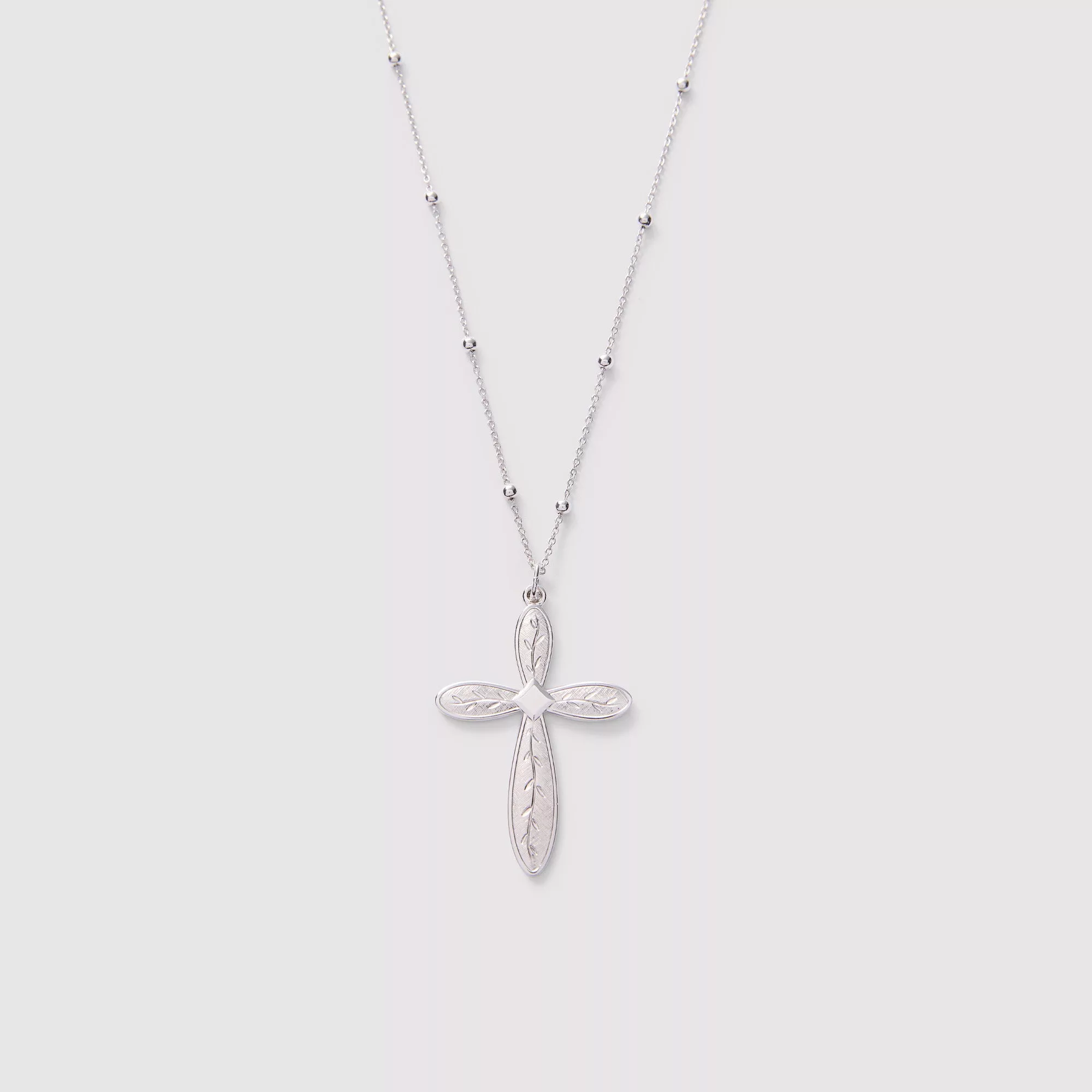Silver cross necklace on a light gray background