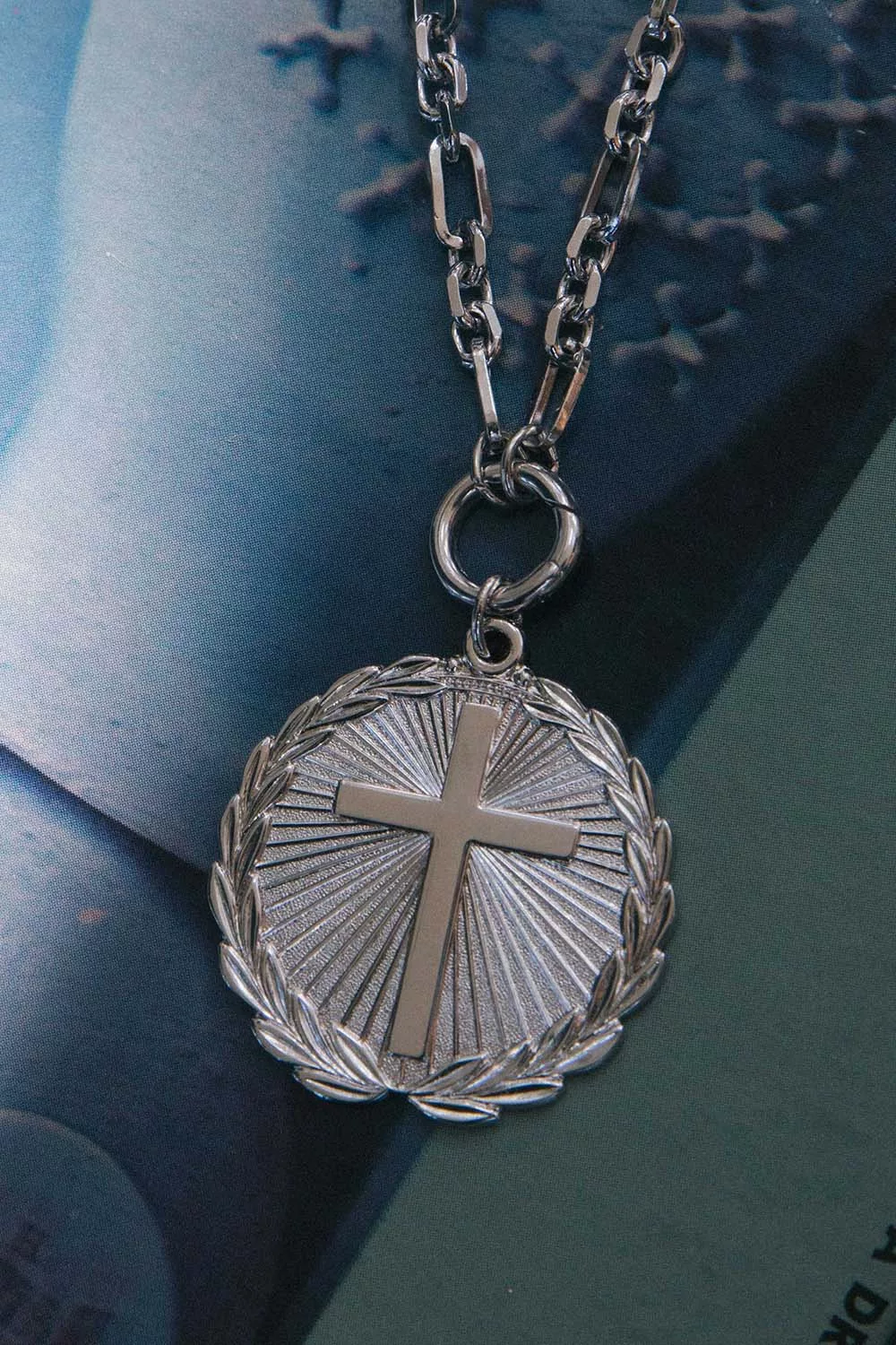 Silver necklace with a cross pendant on a textured surface