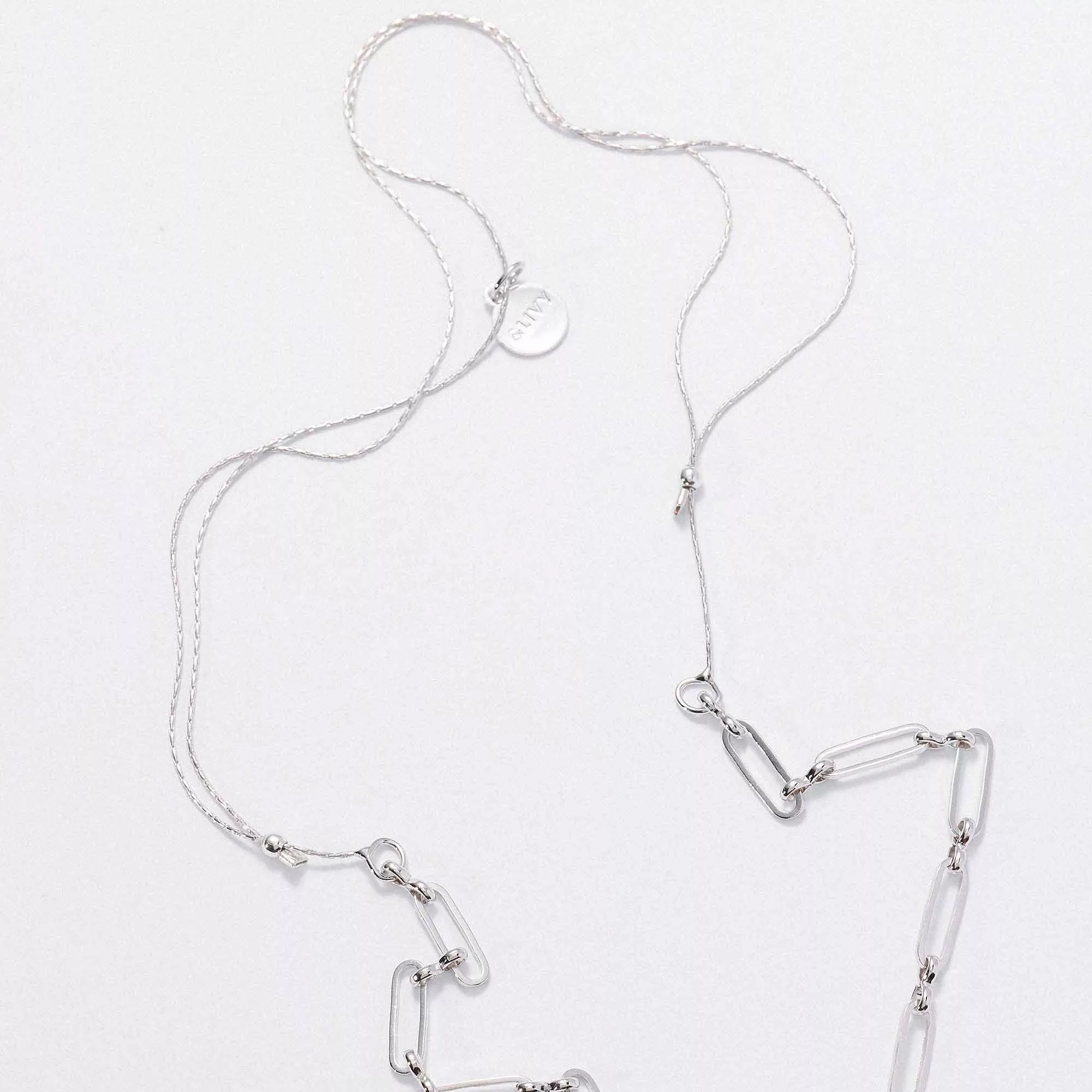 &LIVY silver expandable paperclip intention chain necklace detail showing chain links and branded disc charm