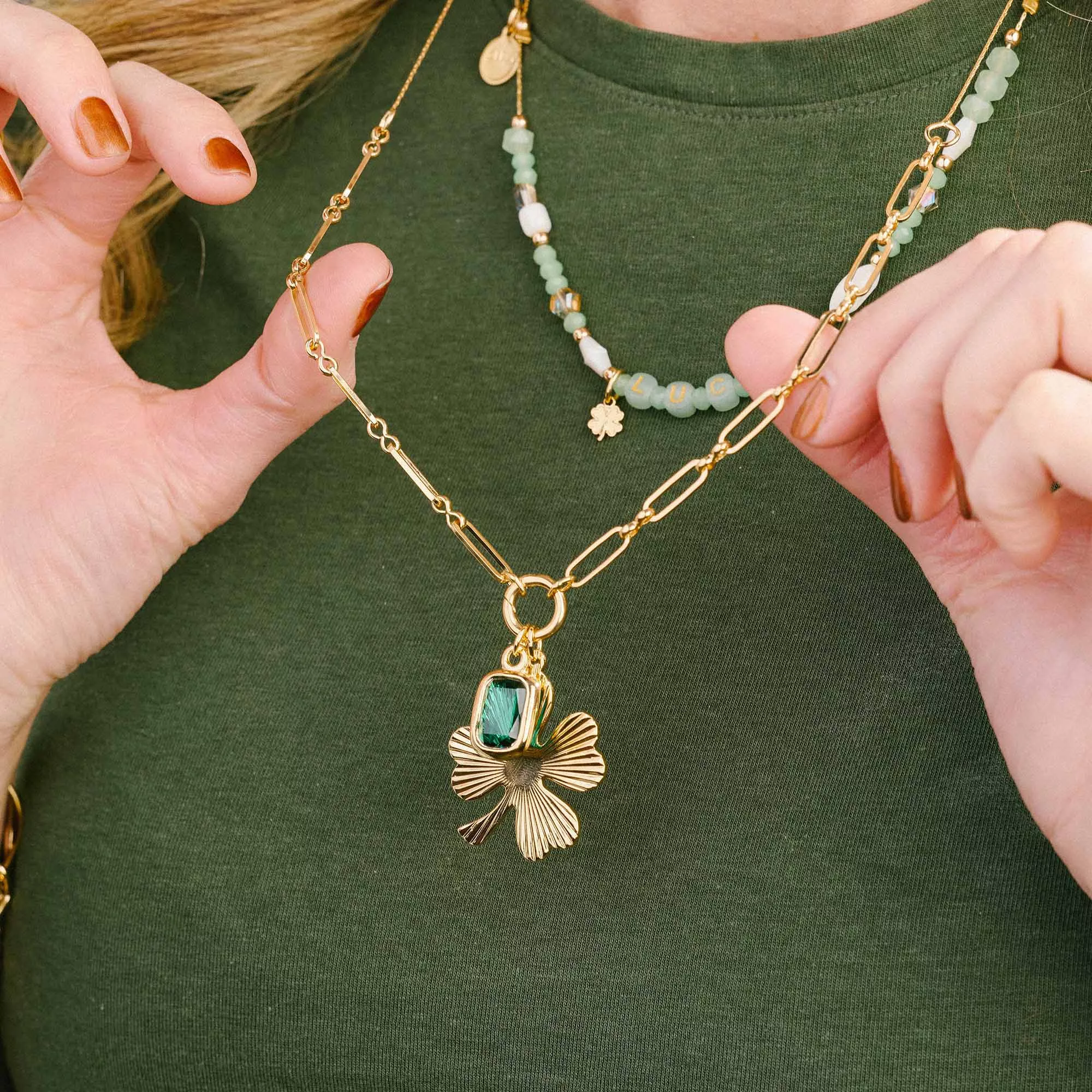 &LIVY Good Things Grow Expandable Necklace in gold worn by model showcasing Shine On Clover charm with emerald crystal layered with beaded necklaces